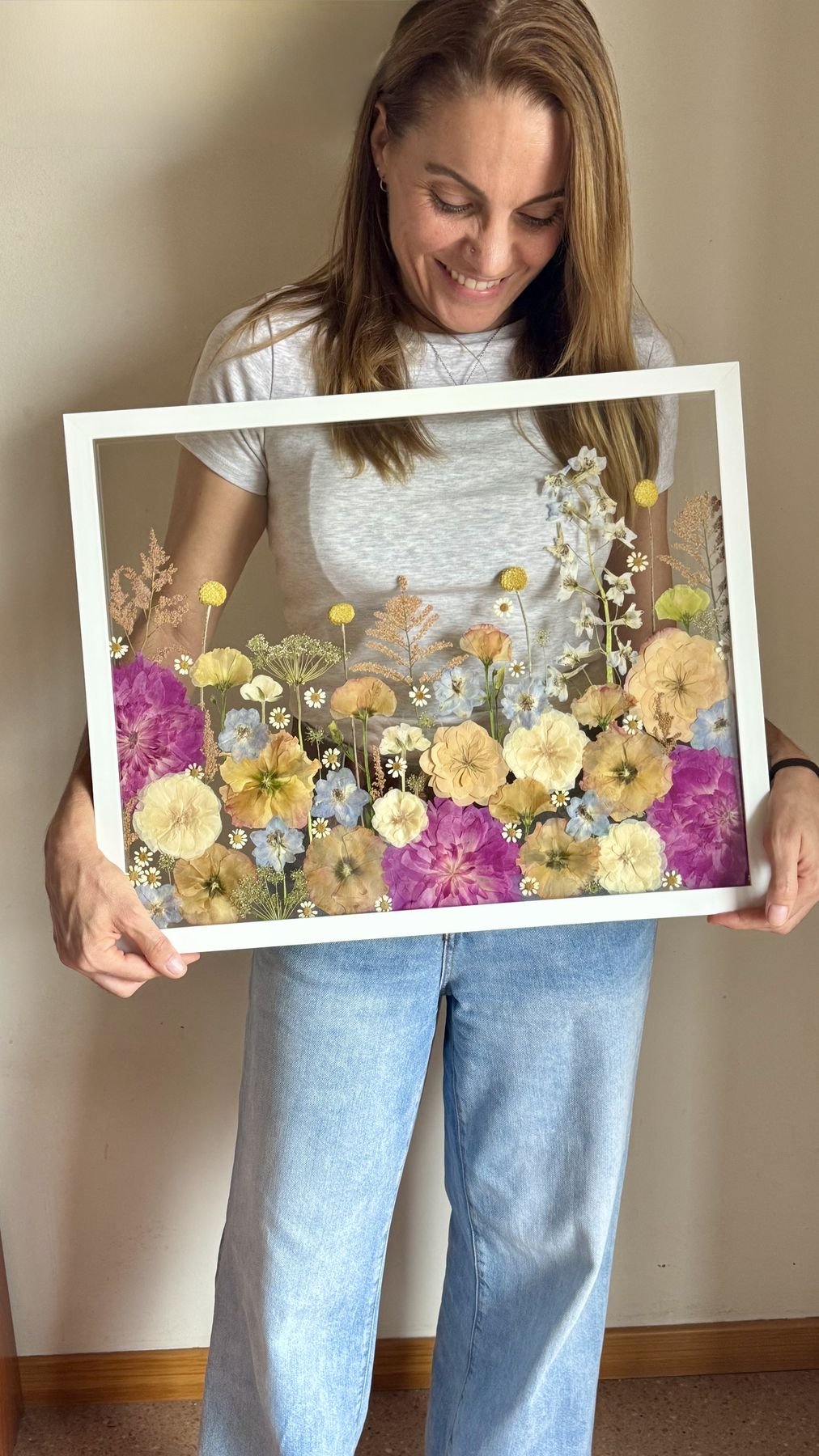 La artesana de Floreneta sostiene un cuadro grande de flores prensadas