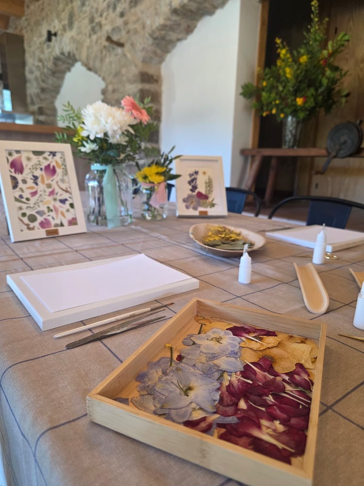 Mesa de taller con flores, bandejas de pétalos y marcos